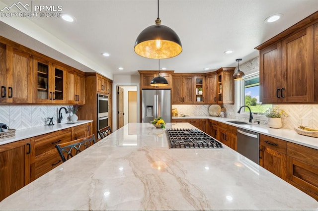 780 Mission Hill Way, Colorado Springs, CO 80921 - kitchen with stainless steel appliances, brown cabinetry, a spacious island, backsplash, and decorative light fixtures