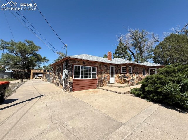 1117 E 6th St, La Junta, CO 81050 - view of front of property featuring stone siding, a chimney, and concrete driveway