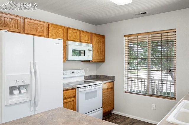 7605 Artisan Pl, Fountain, CO 80817 - kitchen with white appliances, healthy amount of natural light, dark wood finished floors, and brown cabinets