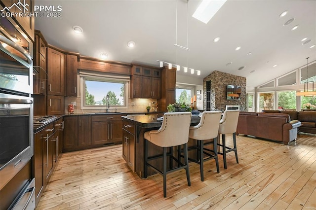 1282 Hill Cir, Colorado Springs, CO 80904 - kitchen featuring dark countertops, a breakfast bar, a center island, light wood-style flooring, and recessed lighting