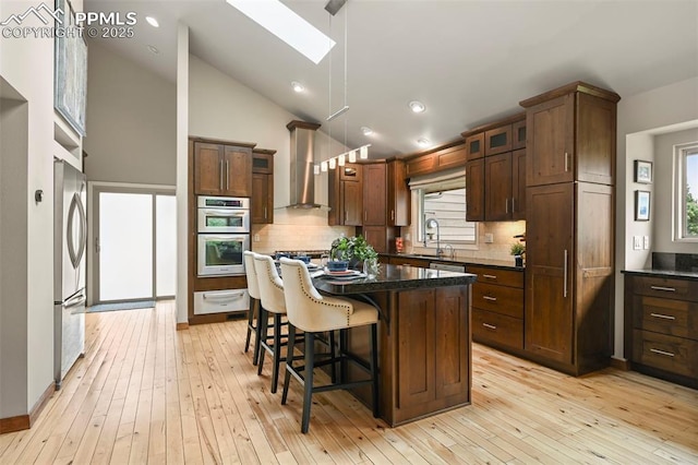1282 Hill Cir, Colorado Springs, CO 80904 - kitchen featuring stainless steel appliances, a skylight, a warming drawer, wall chimney range hood, and tasteful backsplash