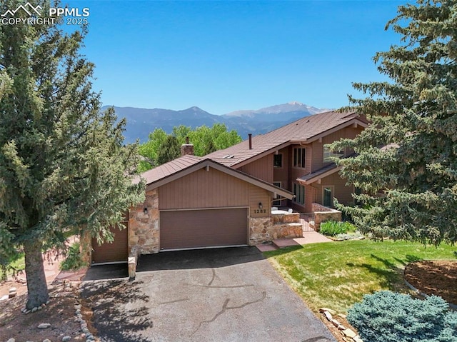 1282 Hill Cir, Colorado Springs, CO 80904 - view of front facade featuring a garage, stone siding, a mountain view, and driveway