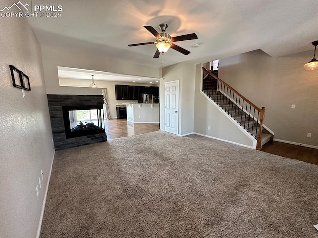 9767 Carnival Ln, Fountain, CO 80817 - unfurnished living room with carpet flooring, a ceiling fan, stairs, and a multi sided fireplace