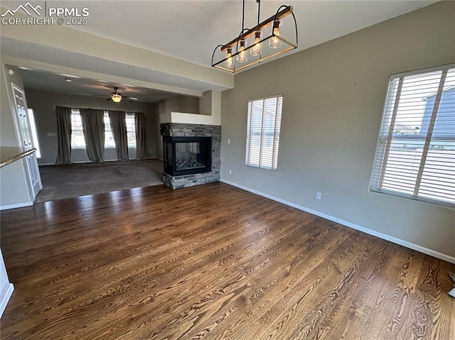 9767 Carnival Ln, Fountain, CO 80817 - unfurnished living room with dark wood-style floors, a chandelier, a ceiling fan, and healthy amount of natural light