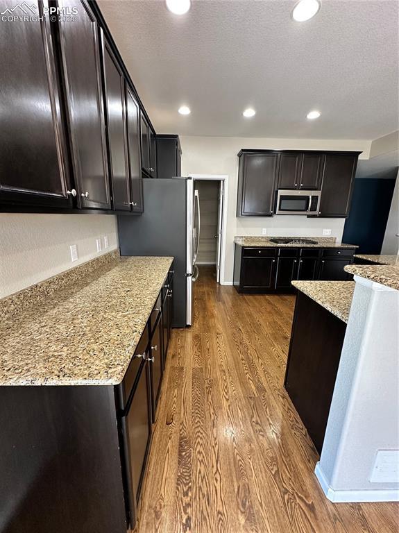 9767 Carnival Ln, Fountain, CO 80817 - kitchen with stainless steel appliances, dark wood-type flooring, light stone countertops, recessed lighting, and a textured ceiling