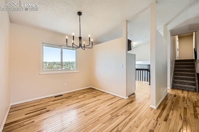 7025 Nettlewood Pl, Colorado Springs, CO 80918 - spare room featuring hardwood / wood-style floors, a chandelier, stairs, and a textured ceiling