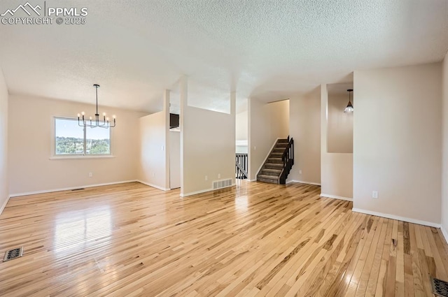 7025 Nettlewood Pl, Colorado Springs, CO 80918 - spare room featuring a chandelier, light wood-type flooring, a textured ceiling, and stairway