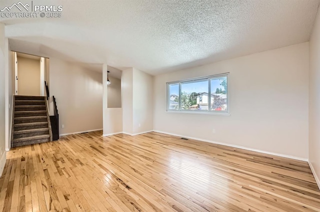 7025 Nettlewood Pl, Colorado Springs, CO 80918 - empty room featuring hardwood / wood-style flooring, a textured ceiling, and stairs