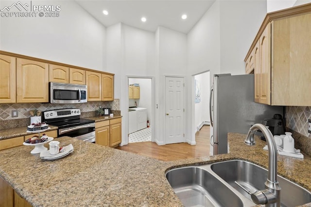 10 Desert Inn Way, Colorado Springs, CO 80921 - kitchen with stainless steel appliances, independent washer and dryer, a towering ceiling, light stone counters, and decorative backsplash