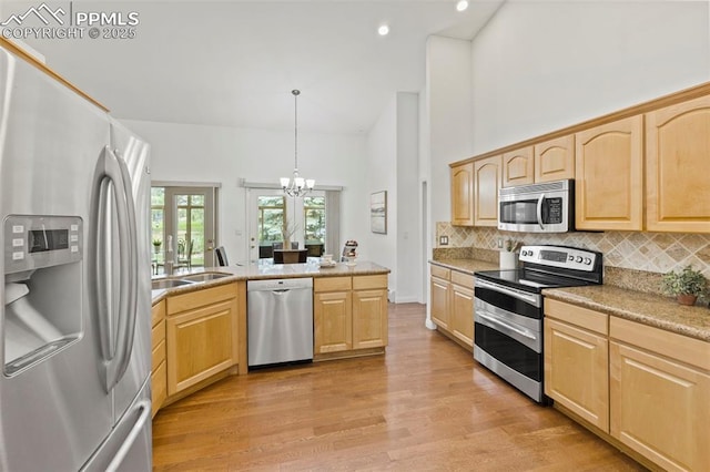 10 Desert Inn Way, Colorado Springs, CO 80921 - kitchen with stainless steel appliances, light brown cabinetry, light wood-style flooring, backsplash, and a towering ceiling
