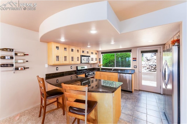 616 Tierra Verde Ct, Colorado Springs, CO 80904 - kitchen with appliances with stainless steel finishes, a peninsula, light brown cabinetry, a breakfast bar, and glass insert cabinets