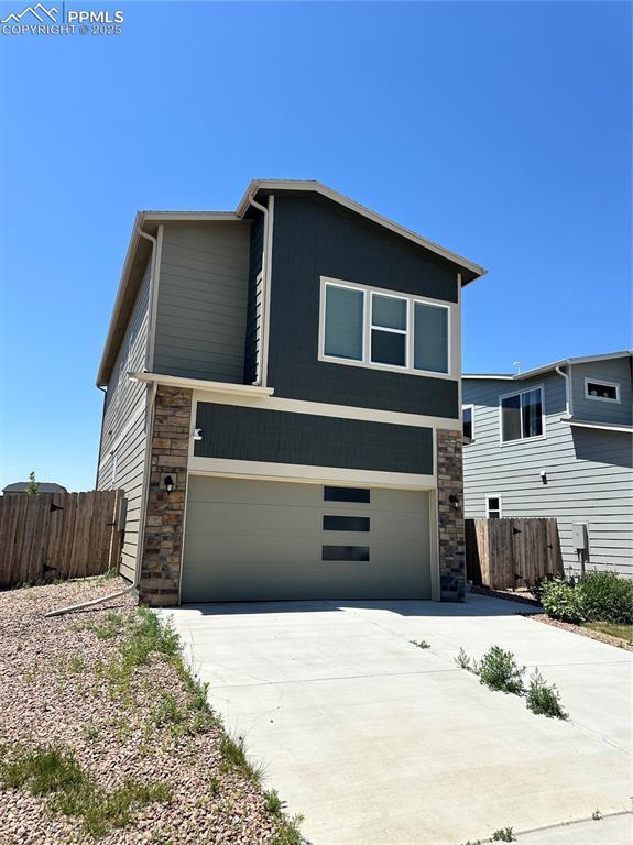 11489 Piping Plover Pl, Colorado Springs, CO 80925 - view of front of home featuring stone siding, driveway, and a garage