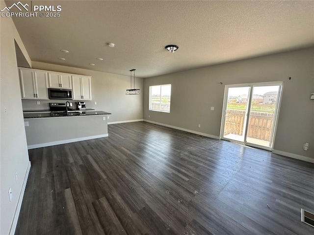 11489 Piping Plover Pl, Colorado Springs, CO 80925 - unfurnished living room featuring dark wood finished floors, a textured ceiling, and recessed lighting