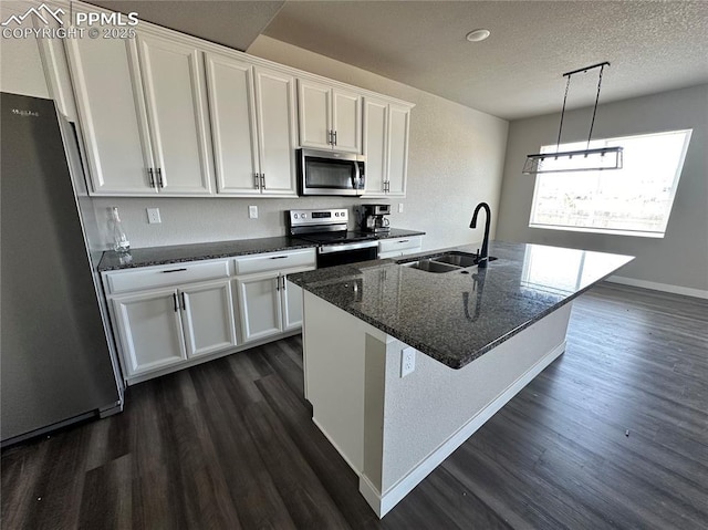 11489 Piping Plover Pl, Colorado Springs, CO 80925 - kitchen featuring stainless steel appliances, dark wood-style floors, white cabinetry, a center island with sink, and dark stone countertops