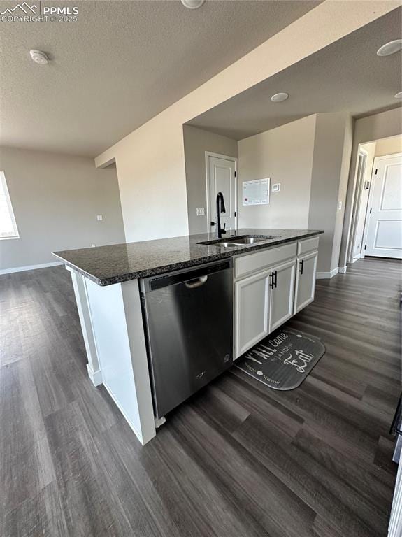 11489 Piping Plover Pl, Colorado Springs, CO 80925 - kitchen with stainless steel dishwasher, a kitchen island with sink, dark wood-style floors, white cabinets, and dark stone counters