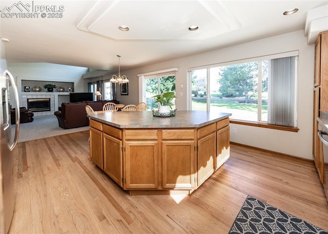 2457 Craycroft Dr, Colorado Springs, CO 80920 - kitchen featuring light wood finished floors, stainless steel fridge, a kitchen island, a tiled fireplace, and a chandelier