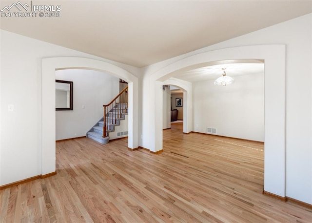 2457 Craycroft Dr, Colorado Springs, CO 80920 - spare room featuring light wood finished floors, arched walkways, stairs, and a chandelier