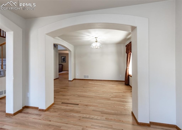 2457 Craycroft Dr, Colorado Springs, CO 80920 - empty room with arched walkways, light wood-type flooring, and a chandelier