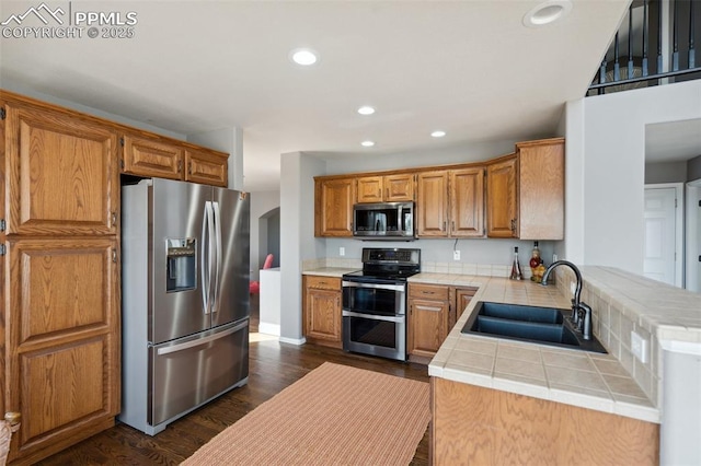 12275 Oregon Wagon Trl, Elbert, CO 80106 - kitchen with appliances with stainless steel finishes, tile countertops, recessed lighting, dark wood-style floors, and arched walkways