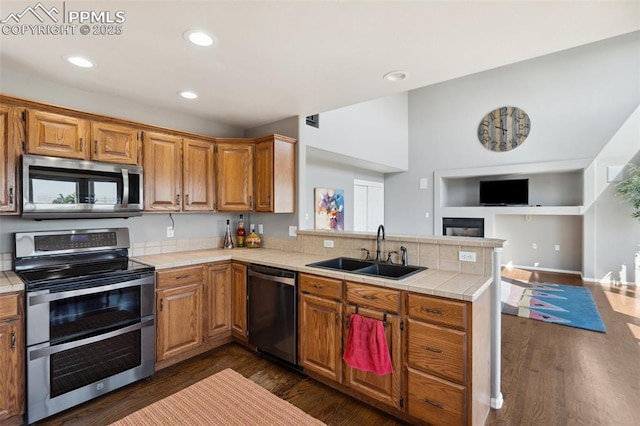 12275 Oregon Wagon Trl, Elbert, CO 80106 - kitchen featuring appliances with stainless steel finishes, a peninsula, tile counters, dark wood finished floors, and open floor plan