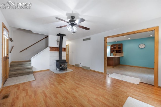 1112 W 4th St, Florence, CO 81226 - unfurnished living room with a wood stove, stairs, wood finished floors, and ceiling fan