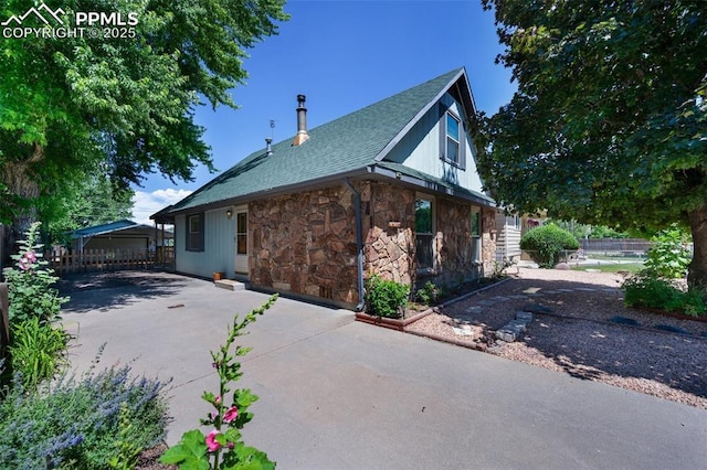 1112 W 4th St, Florence, CO 81226 - view of side of home with stone siding, a shingled roof, and a patio area