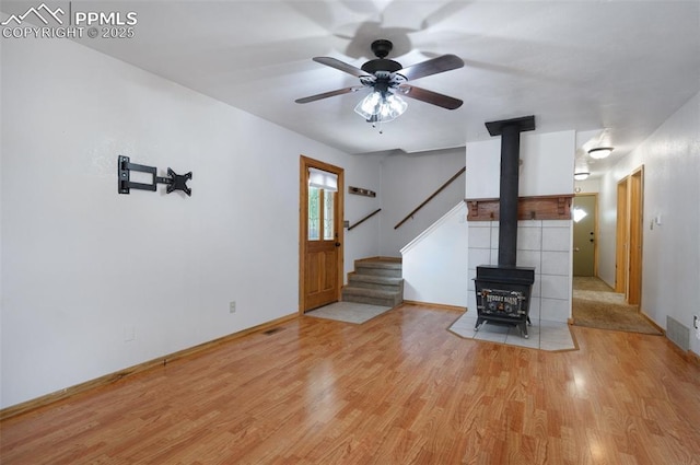 1112 W 4th St, Florence, CO 81226 - unfurnished living room featuring a wood stove, wood finished floors, stairs, and a ceiling fan
