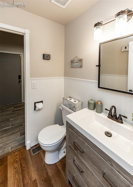 7145 Appletree Loop, Colorado Springs, CO 80925 - bathroom featuring wood finished floors, a wainscoted wall, and vanity