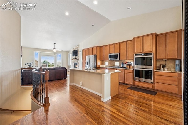 6107 Adamants Dr, Colorado Springs, CO 80924 - kitchen featuring stainless steel appliances, open floor plan, wood finished floors, backsplash, and high vaulted ceiling