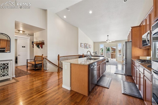 6107 Adamants Dr, Colorado Springs, CO 80924 - kitchen with stainless steel appliances, an island with sink, dark wood-type flooring, brown cabinetry, and high vaulted ceiling