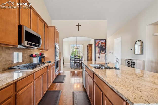 6107 Adamants Dr, Colorado Springs, CO 80924 - kitchen featuring stainless steel appliances, arched walkways, brown cabinets, and light wood finished floors