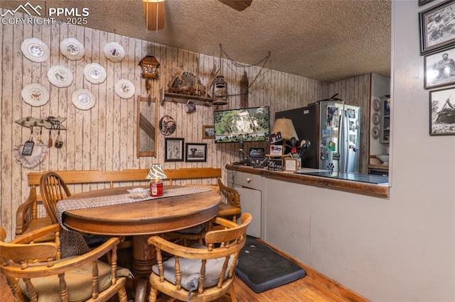 12185 Black Forest Rd, Colorado Springs, CO 80908 - dining area featuring wood finished floors, a textured ceiling, and wood walls