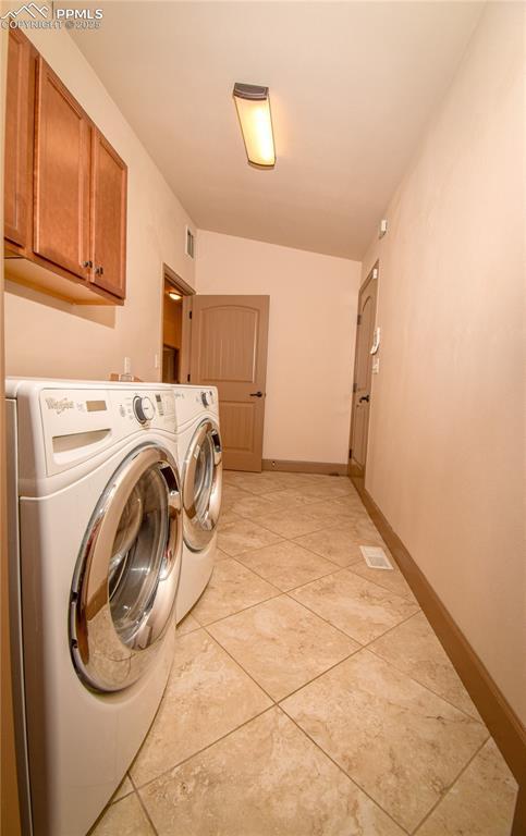 5707 Mark Twain Ln, Pueblo, CO 81008 - laundry area featuring washer and clothes dryer, cabinet space, and light tile patterned floors