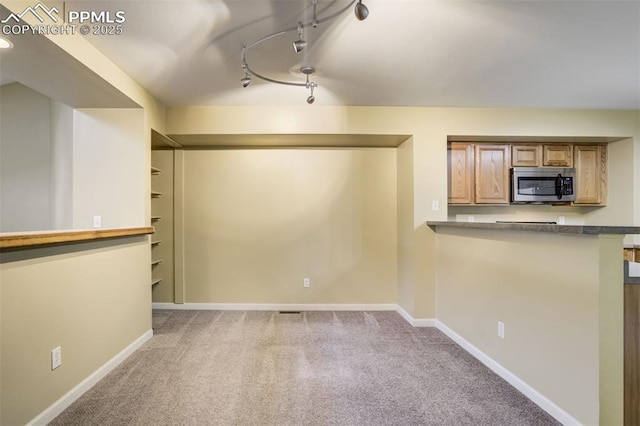 3914 Aspen Leaf Pt, Colorado Springs, CO 80917 - kitchen with stainless steel microwave, carpet floors, track lighting, and dark countertops