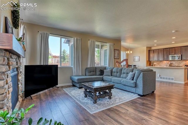 3470 Daydreamer Dr, Colorado Springs, CO 80908 - living room with wood finished floors, a chandelier, recessed lighting, and a stone fireplace