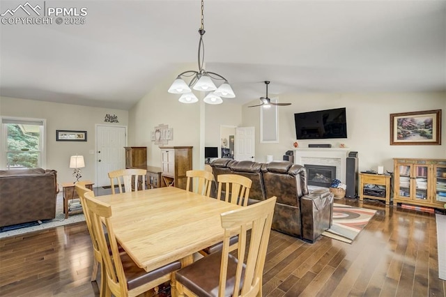 4734 Bunchberry Ln, Colorado Springs, CO 80917 - dining space featuring a fireplace, dark wood-style flooring, vaulted ceiling, and ceiling fan