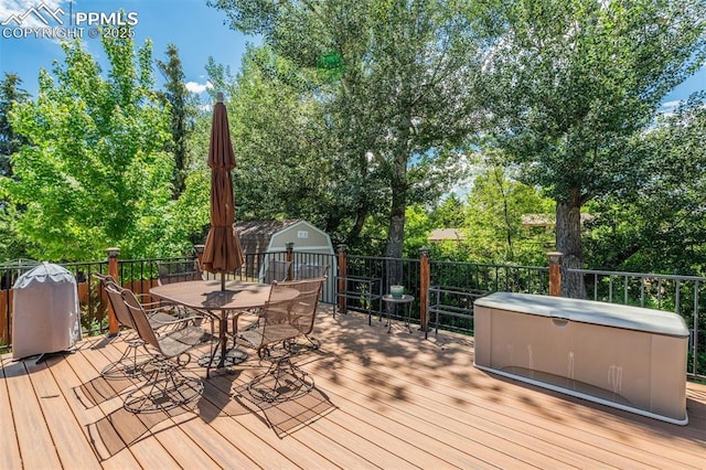 4734 Bunchberry Ln, Colorado Springs, CO 80917 - wooden terrace featuring outdoor dining space, a storage unit, and view of wooded area