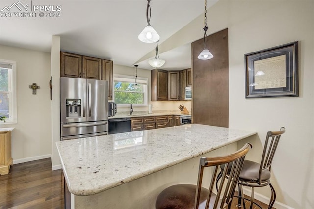 4734 Bunchberry Ln, Colorado Springs, CO 80917 - kitchen featuring appliances with stainless steel finishes, dark wood-style floors, light stone countertops, a kitchen breakfast bar, and vaulted ceiling