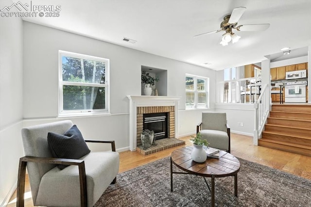 6275 Montarbor Dr, Colorado Springs, CO 80918 - living area featuring light wood-style floors, a ceiling fan, a fireplace, and stairs