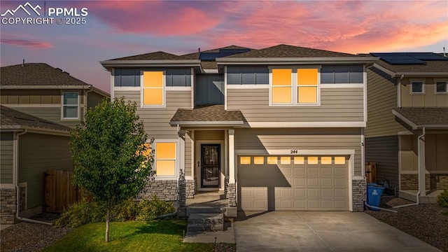 244 S Chipeta Way, Lochbuie, CO 80603 - view of front of house with an attached garage, driveway, stone siding, and a shingled roof