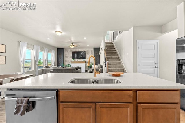 244 S Chipeta Way, Lochbuie, CO 80603 - kitchen featuring stainless steel appliances, open floor plan, ceiling fan, brown cabinetry, and light wood-type flooring