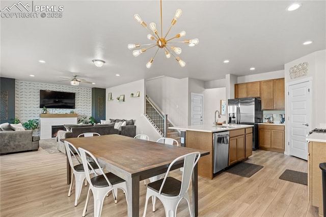 244 S Chipeta Way, Lochbuie, CO 80603 - dining space with light wood-type flooring, recessed lighting, ceiling fan, an accent wall, and a lit fireplace