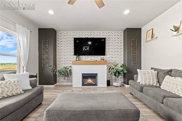 244 S Chipeta Way, Lochbuie, CO 80603 - living area featuring an accent wall, recessed lighting, ceiling fan, a glass covered fireplace, and wood finished floors