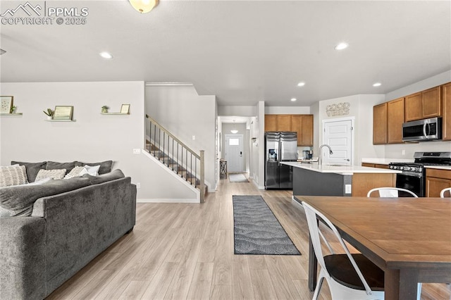 244 S Chipeta Way, Lochbuie, CO 80603 - kitchen with appliances with stainless steel finishes, open floor plan, light countertops, a center island with sink, and brown cabinets