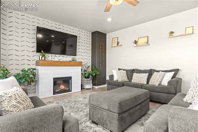 244 S Chipeta Way, Lochbuie, CO 80603 - living room with a ceiling fan, an accent wall, wood finished floors, a glass covered fireplace, and wallpapered walls