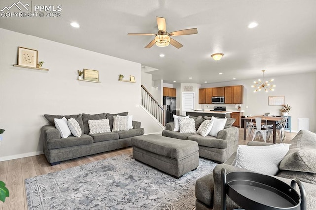 244 S Chipeta Way, Lochbuie, CO 80603 - living room featuring light wood-style flooring, a ceiling fan, stairs, recessed lighting, and a chandelier