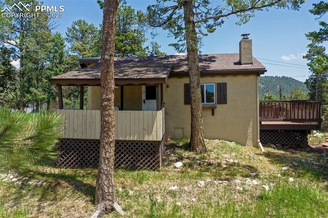 205 N Laurel St, Woodland Park, CO 80863 - rear view of property with stucco siding, a chimney, a wooden deck, and roof with shingles