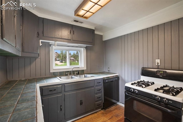 205 N Laurel St, Woodland Park, CO 80863 - kitchen with range with gas cooktop, black dishwasher, tile counters, gray cabinetry, and wooden walls