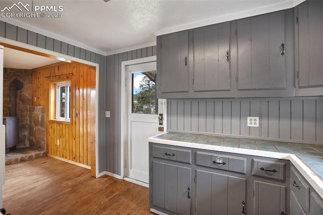 205 N Laurel St, Woodland Park, CO 80863 - kitchen featuring gray cabinetry, tile countertops, wood finished floors, crown molding, and wooden walls