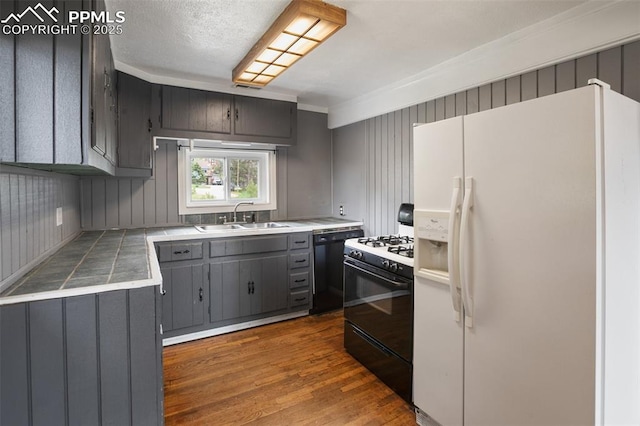 205 N Laurel St, Woodland Park, CO 80863 - kitchen featuring white fridge with ice dispenser, gas range oven, gray cabinetry, ornamental molding, and dark wood-style floors